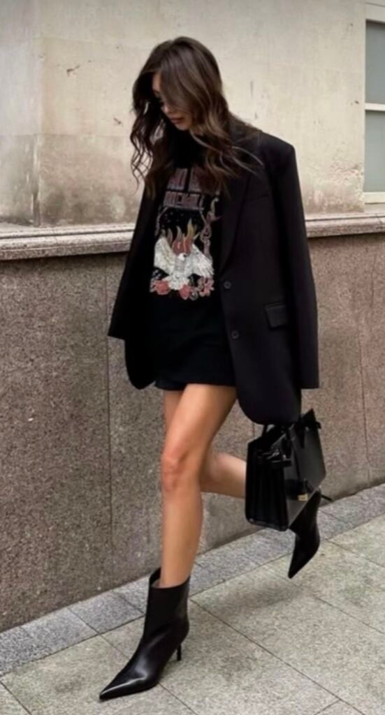 mulher usando moletom feminino preto estampado, blazer preto com mini saia preta e bota de salto cano baixo preta